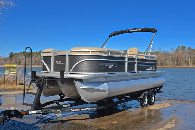 Slide: The Image of 2024 Sun Tracker Party Barge 22 XP3 pontoon boat on trailer by a lake. - 11