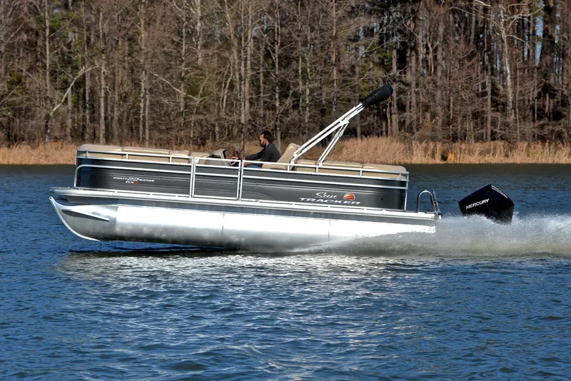 Slide: The Image of 2024 Sun Tracker Party Barge 22 XP3 cruising on a lake with forest backdrop. - 3