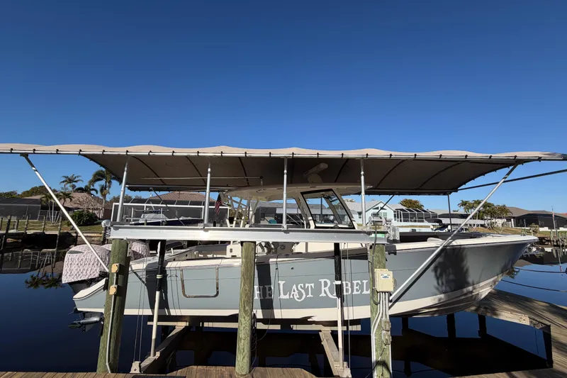 Slide: The Image of 2016 Cobia 344 Center Console boat docked with canopy, named "The Last Rebel." - 10