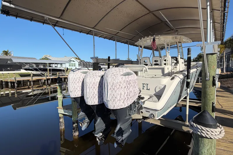 Slide: The Image of 2016 Cobia 344 Center Console boat docked under canopy with twin outboard engines. - 11