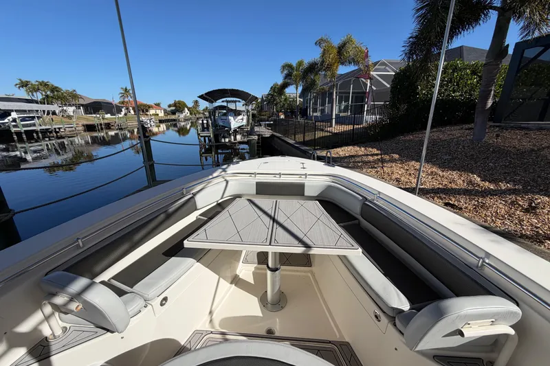 Slide: The Image of 2016 Cobia 344 Center Console boat docked by waterfront homes, featuring spacious seating and table. - 20