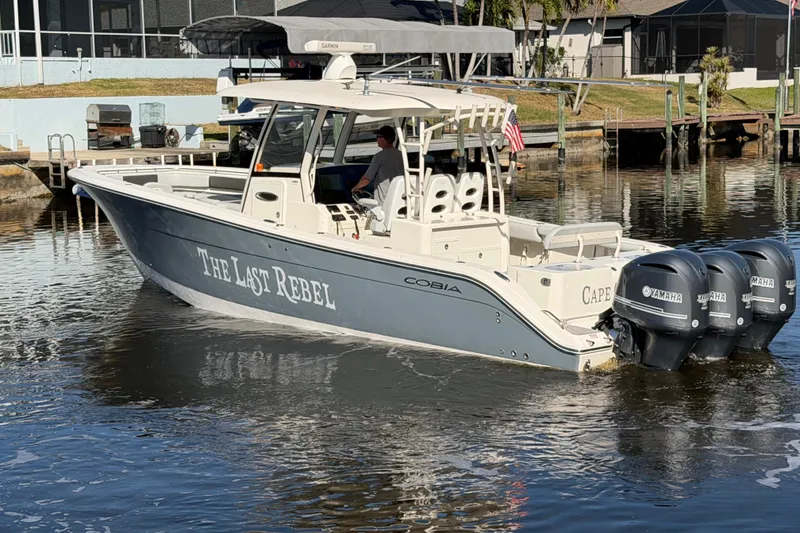 Slide: The Image of 2016 Cobia 344 Center Console boat with triple Yamaha engines on a calm waterway. - 3