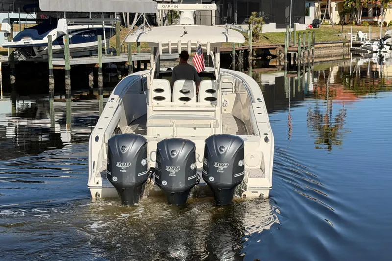 Slide: The Image of 2016 Cobia 344 Center Console boat with triple Yamaha engines on calm water. - 7