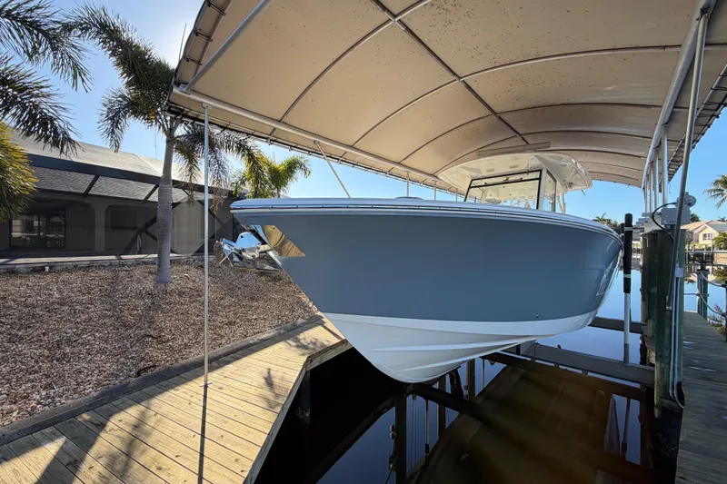 Slide: The Image of 2016 Cobia 344 Center Console boat docked under canopy with palm trees. - 8