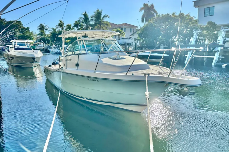 The Image of 2004 Pursuit 3070 Offshore boat docked in sunny marina with palm trees. - 0