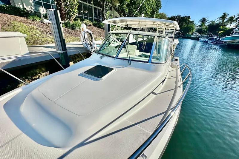 Slide: The Image of 2004 Pursuit 3070 Offshore boat docked in a serene canal setting. - 14