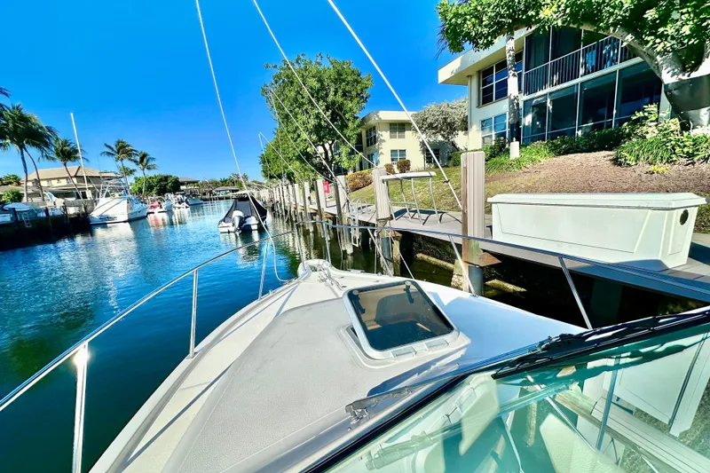 Slide: The Image of 2004 Pursuit 3070 Offshore boat docked in a sunny marina with palm trees. - 17