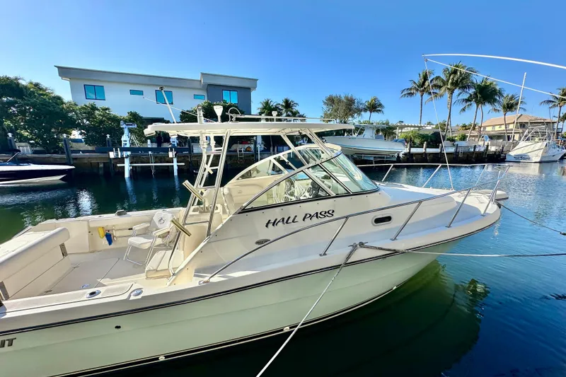 Slide: The Image of 2004 Pursuit 3070 Offshore boat docked in sunny marina with palm trees. - 2