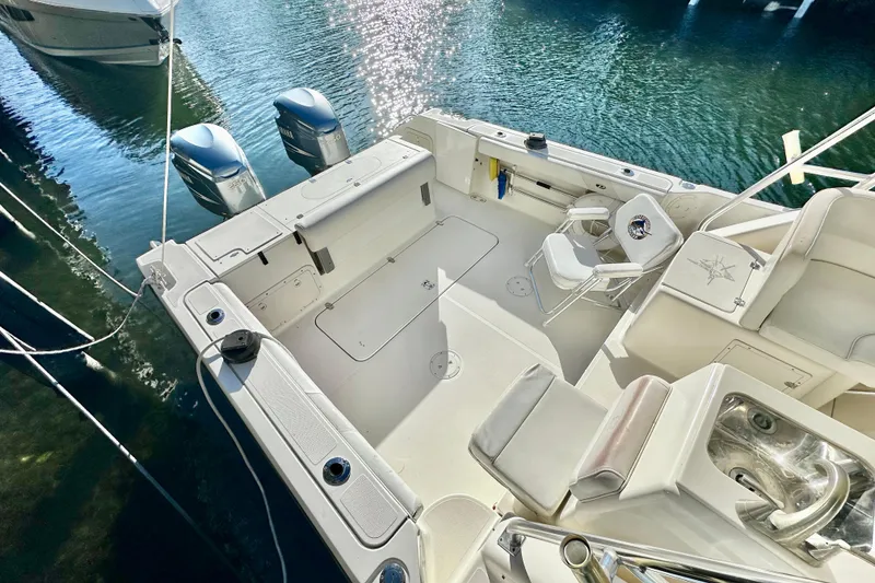 Slide: The Image of 2004 Pursuit 3070 Offshore boat with dual engines, docked on calm water. - 22