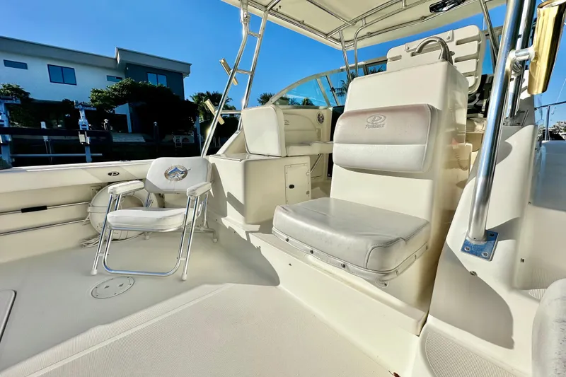 Slide: The Image of 2004 Pursuit 3070 Offshore boat interior with seating and helm, under clear blue sky. - 40