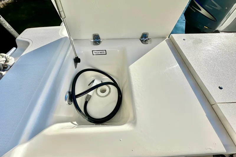 Slide: The Image of Freshwater compartment on 2004 Pursuit 3070 Offshore boat, featuring hose and storage area. - 45