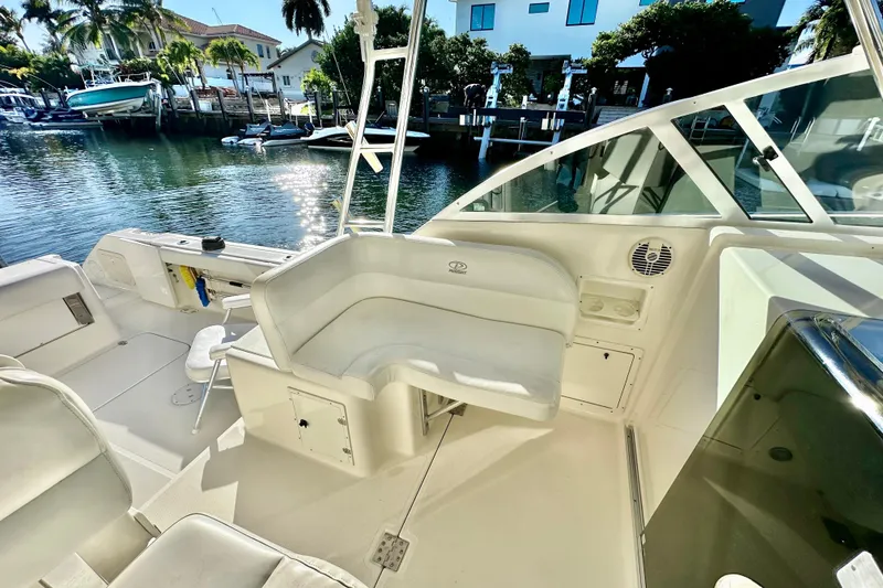 Slide: The Image of 2004 Pursuit 3070 Offshore boat interior with seating, docked by waterfront homes. - 54