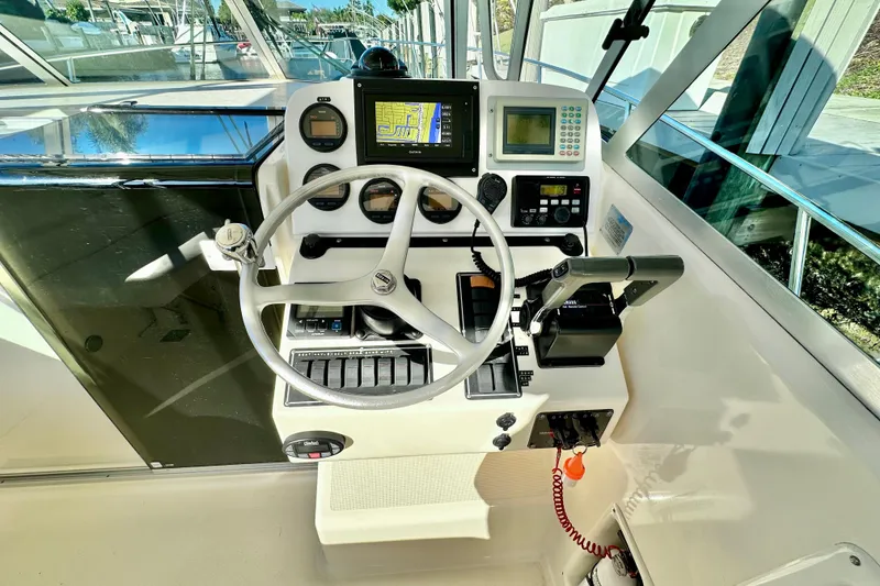 Slide: The Image of 2004 Pursuit 3070 Offshore boat helm with steering wheel and navigation controls. - 58