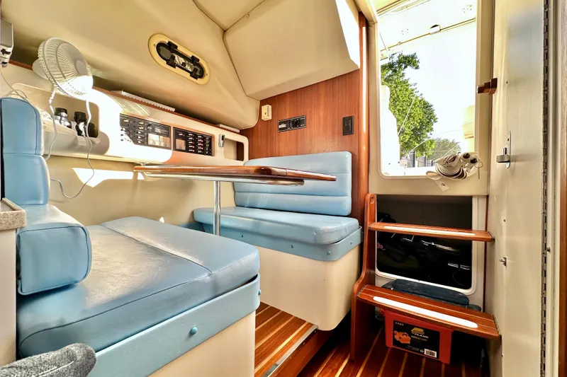 Slide: The Image of 2004 Pursuit 3070 Offshore cabin interior with blue seating and wooden accents. - 67