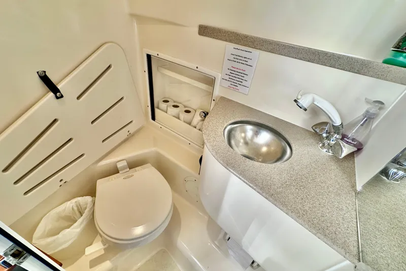 Slide: The Image of Compact bathroom in 2004 Pursuit 3070 Offshore boat with toilet, sink, and storage. - 81