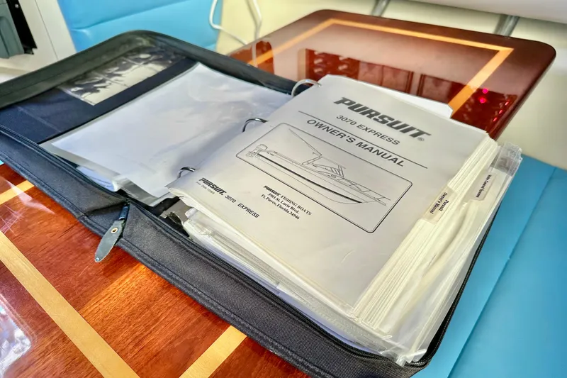 Slide: The Image of Owner's manual for 2004 Pursuit 3070 Offshore boat on a wooden table. - 87