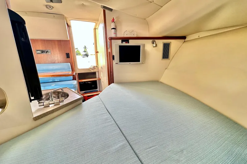 Slide: The Image of Interior of 2004 Pursuit 3070 Offshore boat with bed, sink, and seating area. - 90