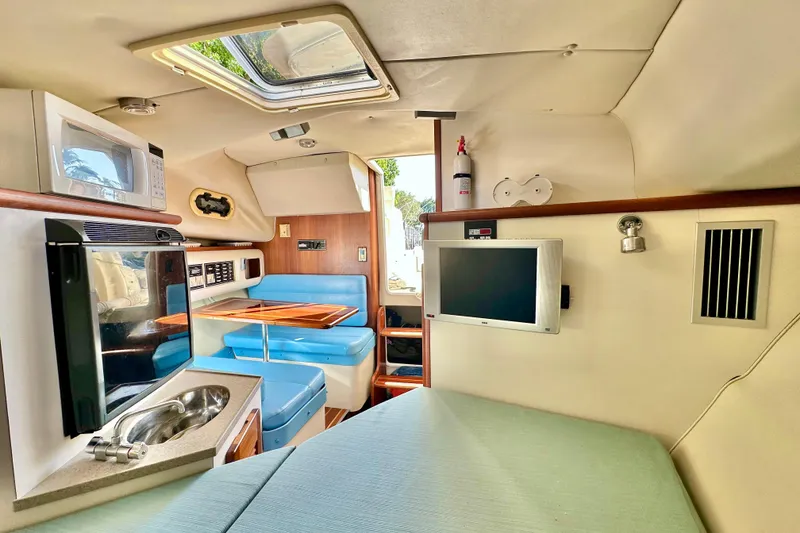 Slide: The Image of Interior of 2004 Pursuit 3070 Offshore boat with kitchenette, seating, and TV. - 91