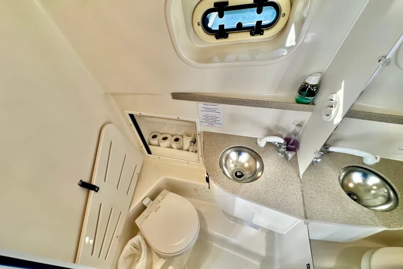 Slide: The Image of 2004 Pursuit 3070 Offshore boat bathroom with sink, toilet, and storage. - 97