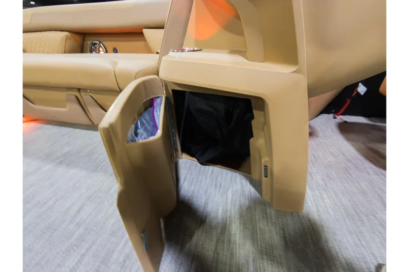 Slide: The Image of 2026 Godfrey Sweetwater 22' Tritoon interior storage compartment with open door, beige upholstery. - 11