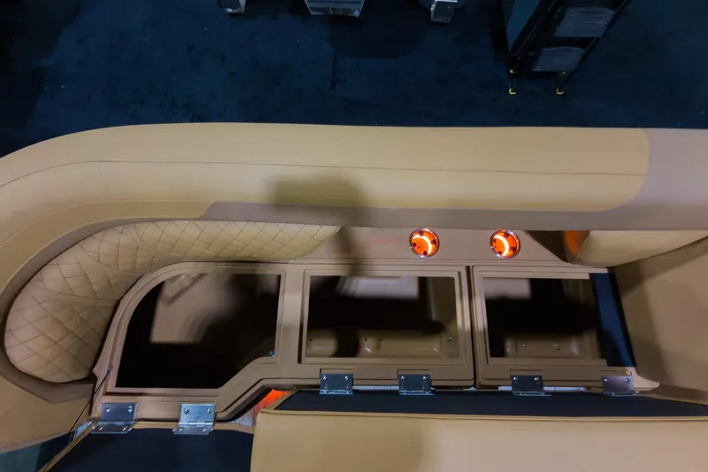 Slide: The Image of 2026 Godfrey Sweetwater 22' Tritoon interior with tan split bench seating and storage compartments. - 6