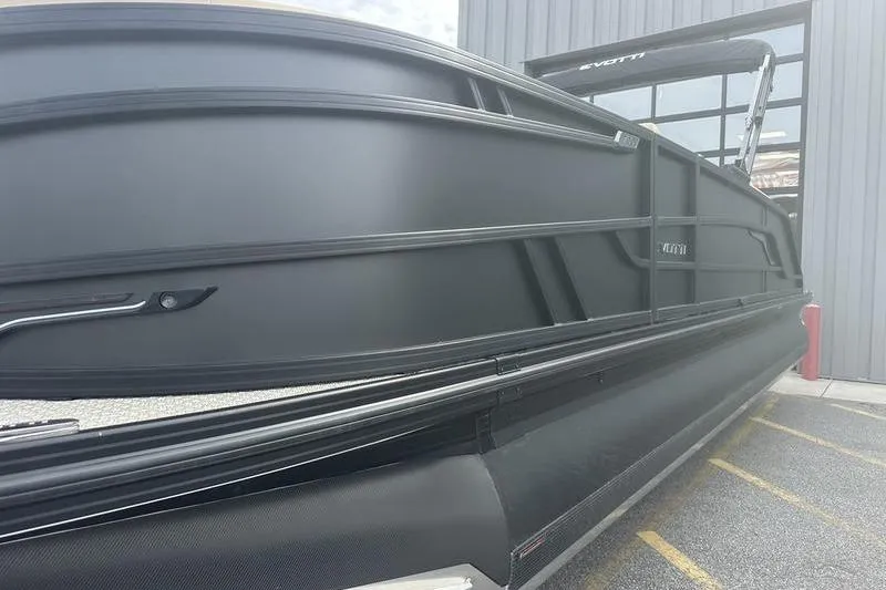 Slide: The Image of 2026 Evotti 723CS pontoon boat with sleek black exterior, docked near a modern building. - 17