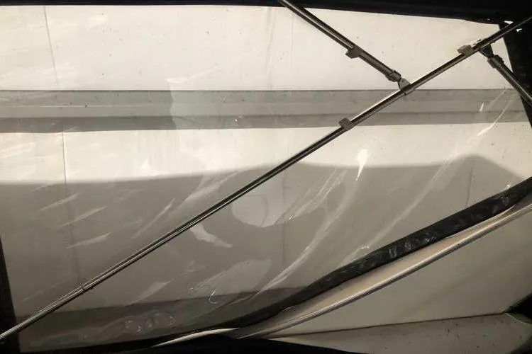 Slide: The Image of 1997 Bayliner 3988 Motoryacht window with metal support rods and clear plastic covering. - 16