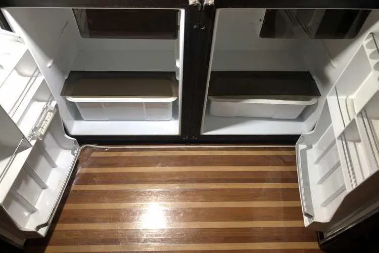 Slide: The Image of Open refrigerator on 1997 Bayliner 3988 Motoryacht, showcasing empty shelves and wooden flooring. - 33