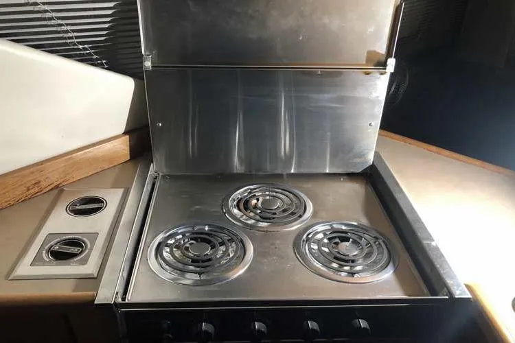 Slide: The Image of 1997 Bayliner 3988 Motoryacht kitchen stove with three burners and metal cover. - 35