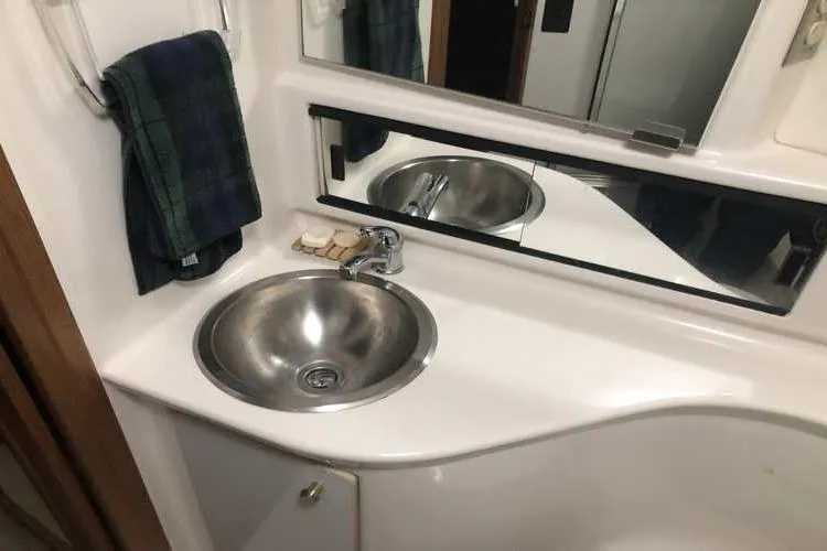 Slide: The Image of Bathroom sink area in 1997 Bayliner 3988 Motoryacht, featuring stainless steel basin and mirror. - 55