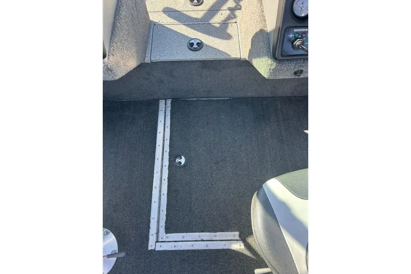 Slide: The Image of Interior of a 2013 Lund 1800 Sport Angler boat, featuring carpeted flooring and seating. - 15