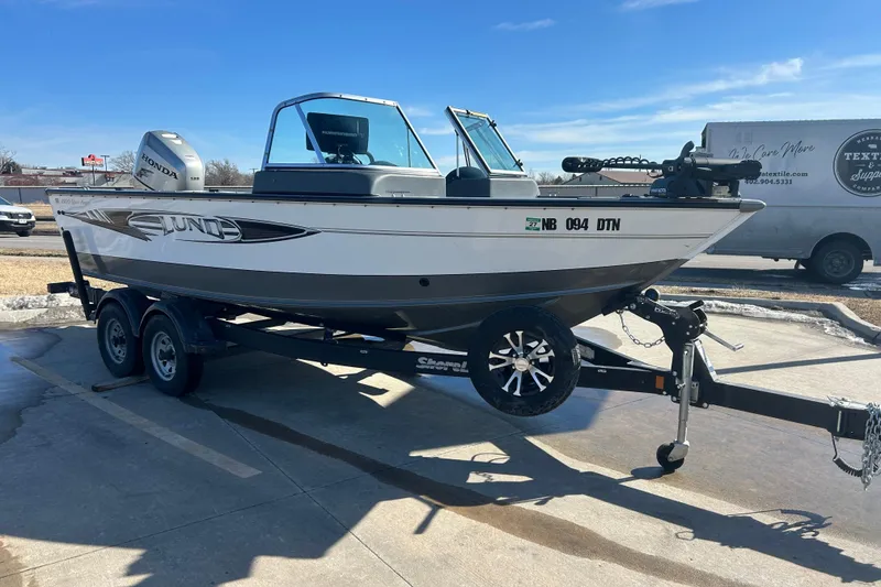 Slide: The Image of 2013 Lund 1800 Sport Angler boat on trailer, featuring Honda outboard motor. - 2