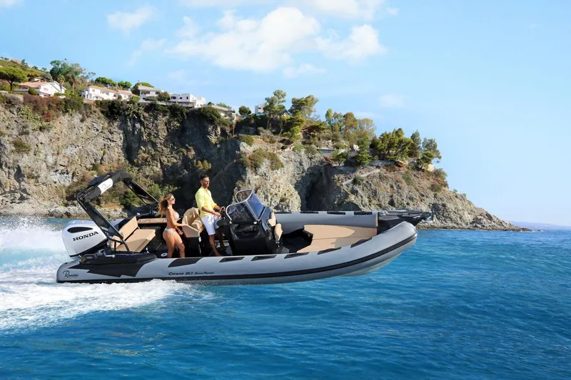 Slide: The Image of 2026 Ranieri Cayman 26.0 Sport Touring boat cruising near rocky coastline. - 0