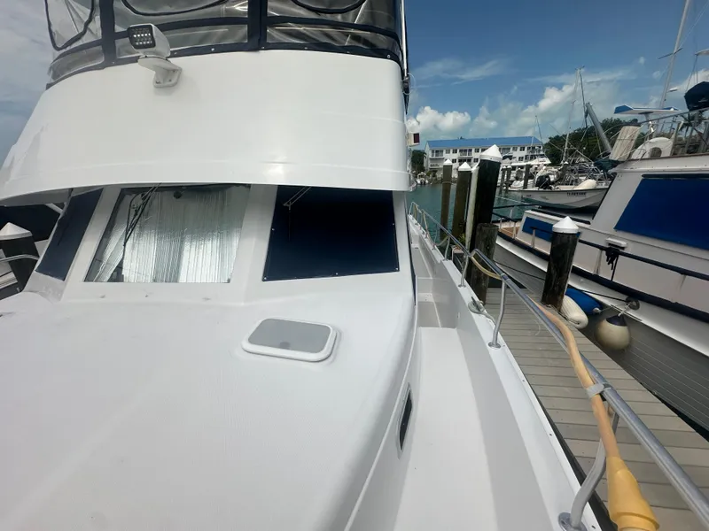 Slide: The Image of 1999 Mainship 430 Trawler docked at marina, showcasing sleek design and spacious deck. - 11