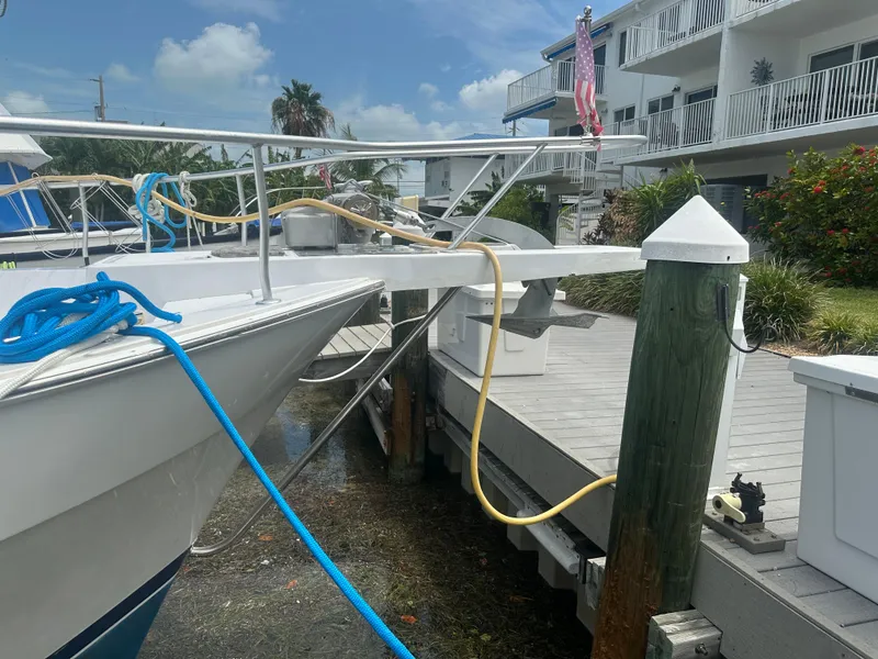 Slide: The Image of 1999 Mainship 430 Trawler docked, with blue and yellow ropes, near waterfront buildings. - 21