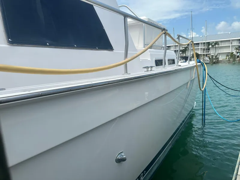 Slide: The Image of 1999 Mainship 430 Trawler docked, side view with water and buildings in background. - 24