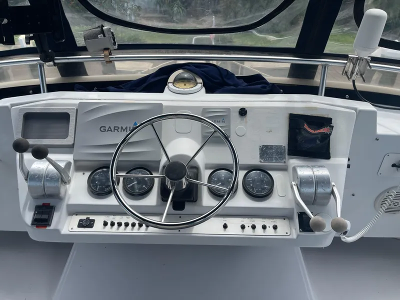Slide: The Image of 1999 Mainship 430 Trawler helm with Garmin navigation, steering wheel, and control gauges. - 30