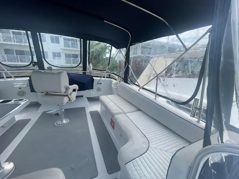 Slide: The Image of 1999 Mainship 430 Trawler interior with seating and helm, featuring large windows and canopy. - 32