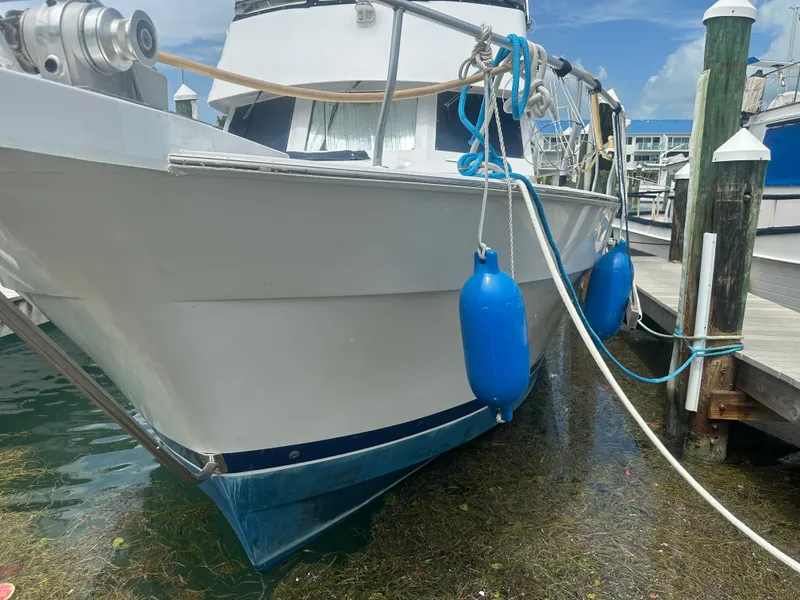 Slide: The Image of 1999 Mainship 430 Trawler docked with blue fenders, clear sky background. - 5
