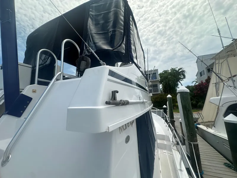 Slide: The Image of 1999 Mainship 430 Trawler docked, featuring sleek design and covered upper deck. - 9