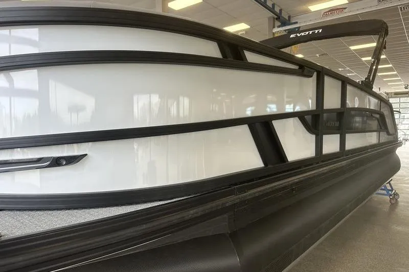 Slide: The Image of 2026 Evotti 723QL pontoon boat with sleek black and white design in showroom. - 11