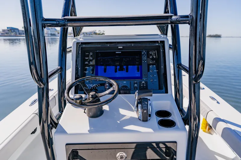 Slide: The Image of 2024 Dorado 25 boat dashboard with steering wheel and navigation display on calm water. - 31