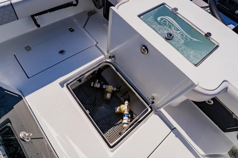 Slide: The Image of 2024 Dorado 25 boat storage compartment with open hatch and visible plumbing components. - 41