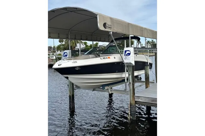 The Image of 2006 Chaparral 246 SSi boat on lift under canopy, docked by waterfront. - 1