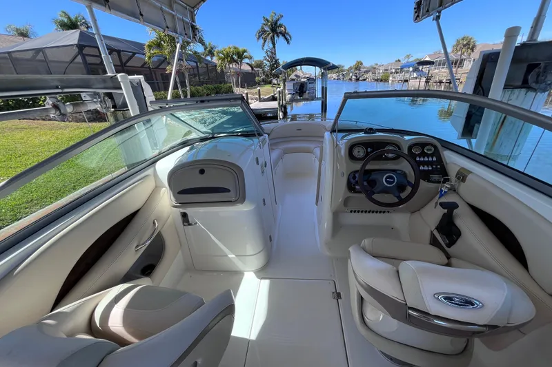 Slide: The Image of 2006 Chaparral 246 SSi boat interior with steering wheel and seating, docked by a canal. - 12