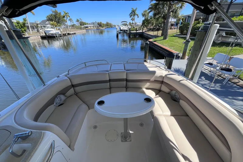 Slide: The Image of 2006 Chaparral 246 SSi boat interior with seating and table, docked by a scenic canal. - 17