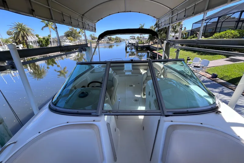 Slide: The Image of 2006 Chaparral 246 SSi boat docked under canopy, reflecting on calm water. - 21