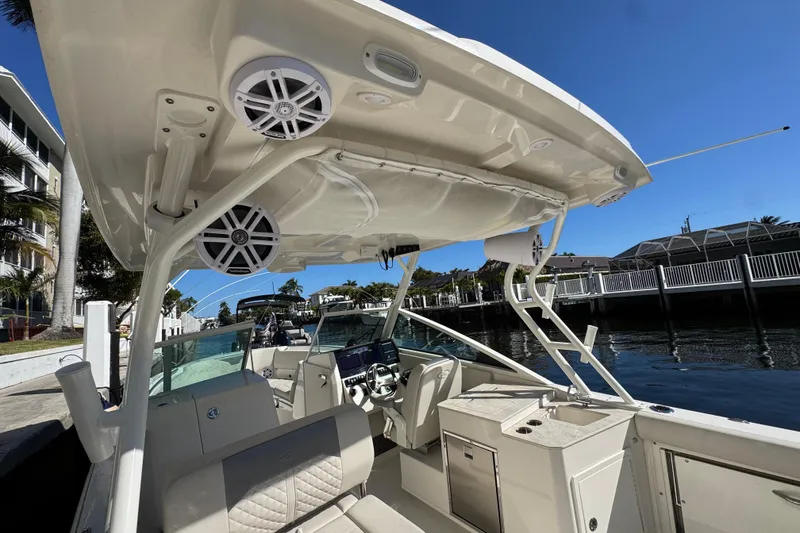 Slide: The Image of 2025 Sailfish 276 DC boat interior with speakers and seating, docked by waterfront homes. - 20