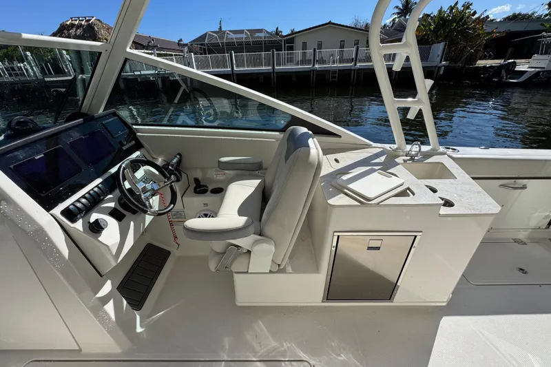 Slide: The Image of 2025 Sailfish 276 DC boat interior with helm, seating, and sink by the water. - 21