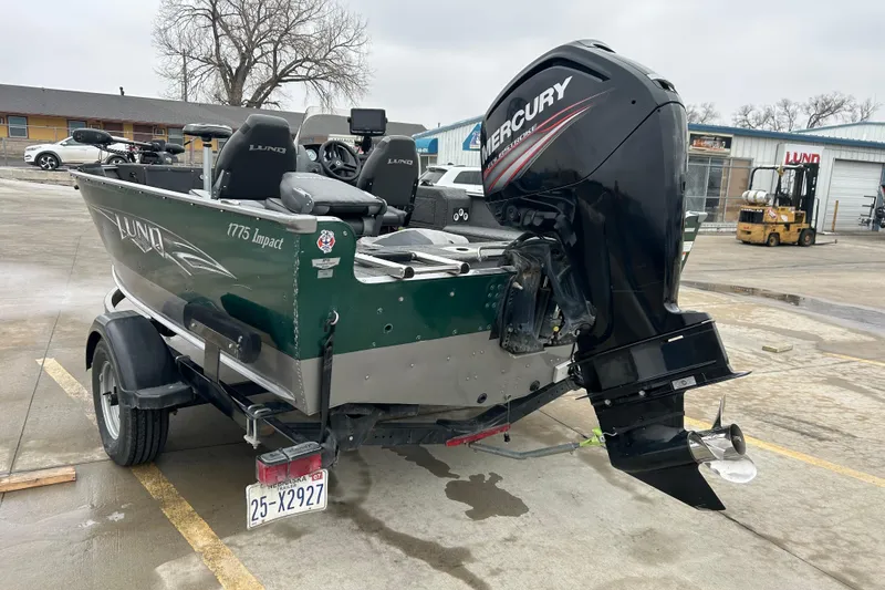 Slide: The Image of 2015 Lund 1775 Impact boat with Mercury outboard motor in a parking lot. - 2